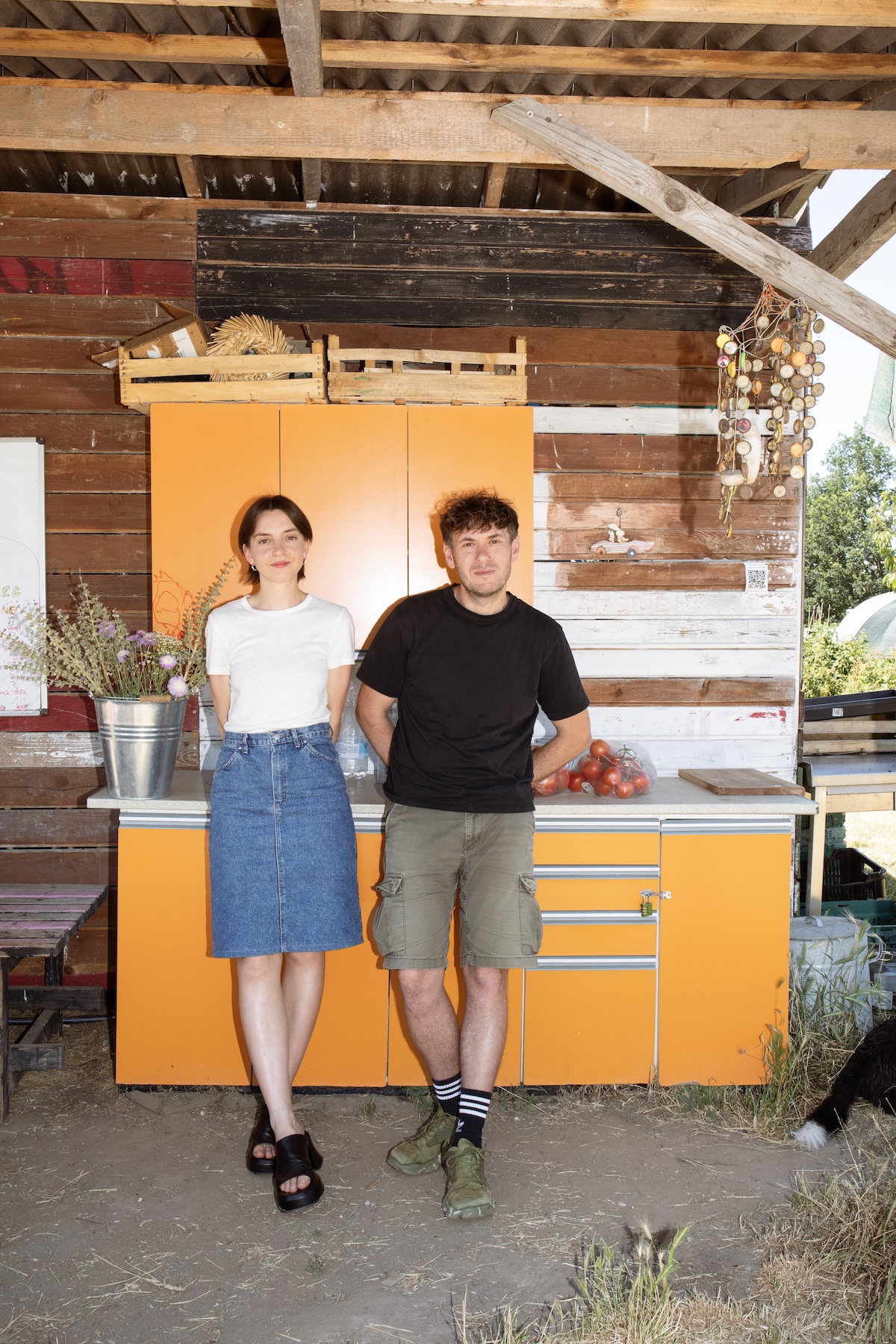 Kochbuchautorin Šárka Otevřel Camrdová und Fotograf Marek Bartoš vor orangefarbenem Küchenschrank in offenem Holzverschlag 