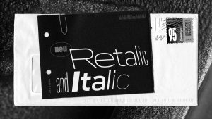 Auf einem weißen Briefumschlag liegt eine schwarze Postkarte, die mit den neuen kursicen Schnitten der Schrift DIN bedruckt ist.