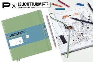 Skizzenbuch „Leuchtturm1917 – Denken mit der Hand“ neben einer geöffneten Seite mit gezeichneter New-York-Stadtszene; daneben liegen Stifte und Wachsmalstifte, oben Schriftzug „P × Leuchtturm1917“.