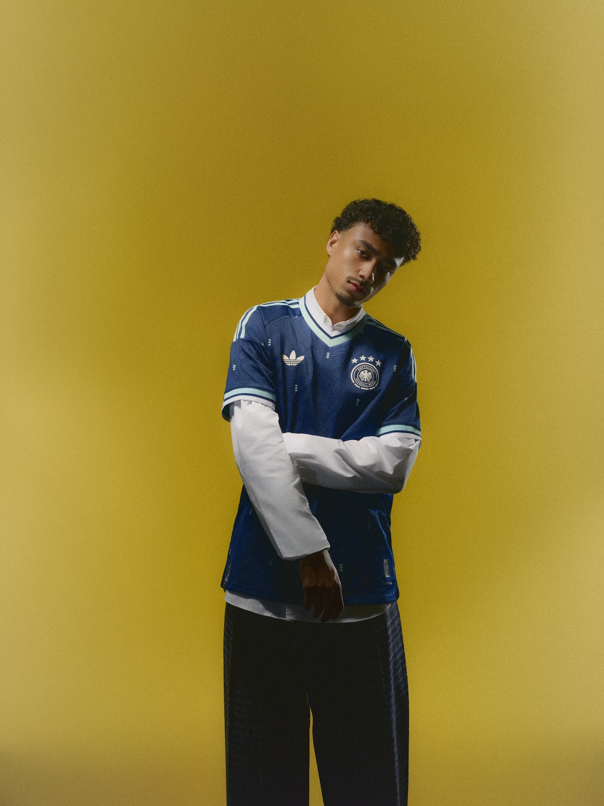 Fußballer im blauen neuen Auswärtstrikot der deutschen Fußballnationalmannschaft vor senfgelber Wand