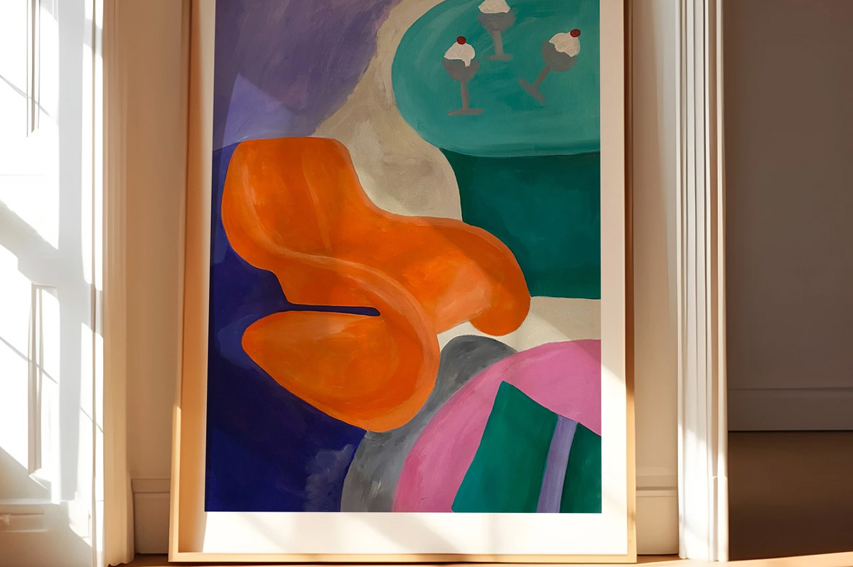 Fine Art Print von Julia Gescher, gerahmt und an eine Wand gelehnt. Das querformatige Bild zeigt eine abstrakte, farbenfrohe Komposition mit einer orangefarbenen organischen Form im Zentrum, umgeben von blauen, grünen, grauen und pinken Flächen. Im oberen rechten Bereich sind zwei stilisierte Eisbecher mit roten Kirschen auf türkisem Grund zu sehen. Das Bild ist in warmem Fensterlicht fotografiert.