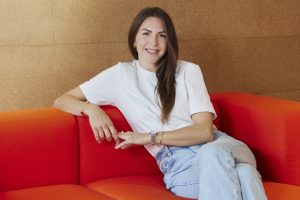 Porträt Jana, Frau sitzt auf einem roten Sofa