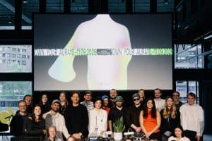 Speaker und Team auf einer Bühne, im Hintergrund großer Screen