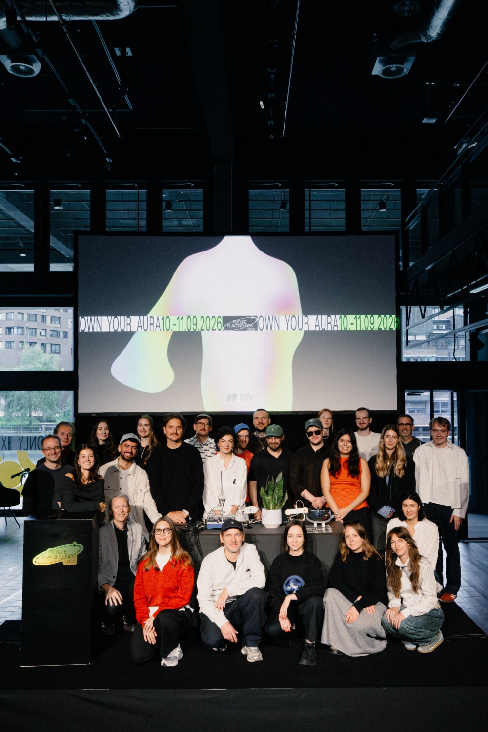 Speaker und Team auf einer Bühne, im Hintergrund großer Screen