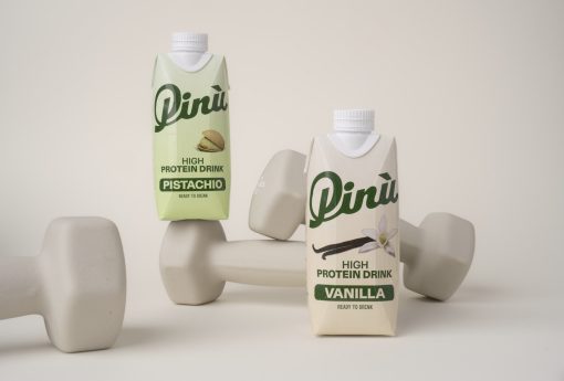 Pinu High Protein Drink in cremefarbenem Packaging mit Pistazie oder Vanilleschote Illustration und auf Hanteln dekoriert