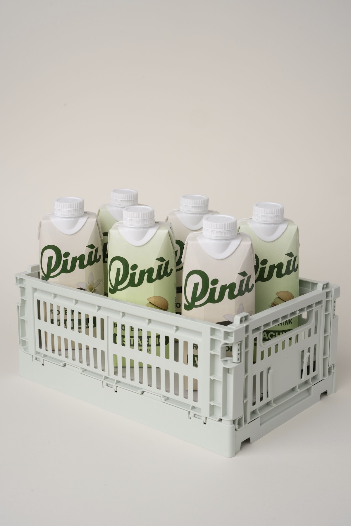 Pinu High Protein Drink in cremefarbenem Packaging in einer gräulichen Plastikkiste inszeniert